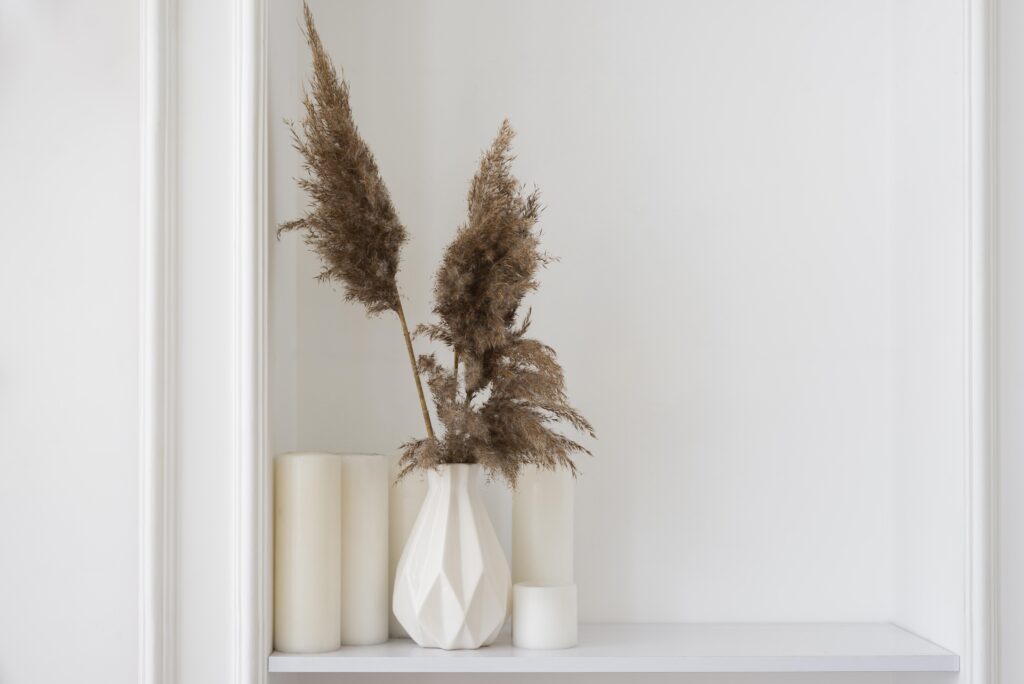 Dekoratives Blumenarrangement mit Kerzen und im Hintergrund eine weiße Wand.